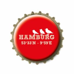 Kronkorken Hamburg Koordinaten, ein Kühlschrankmagnet aus einem Flaschenkorken mit den Hamburg Koordinaten mittig und drei weiße Möwen sitzend und einem Glascabouchon